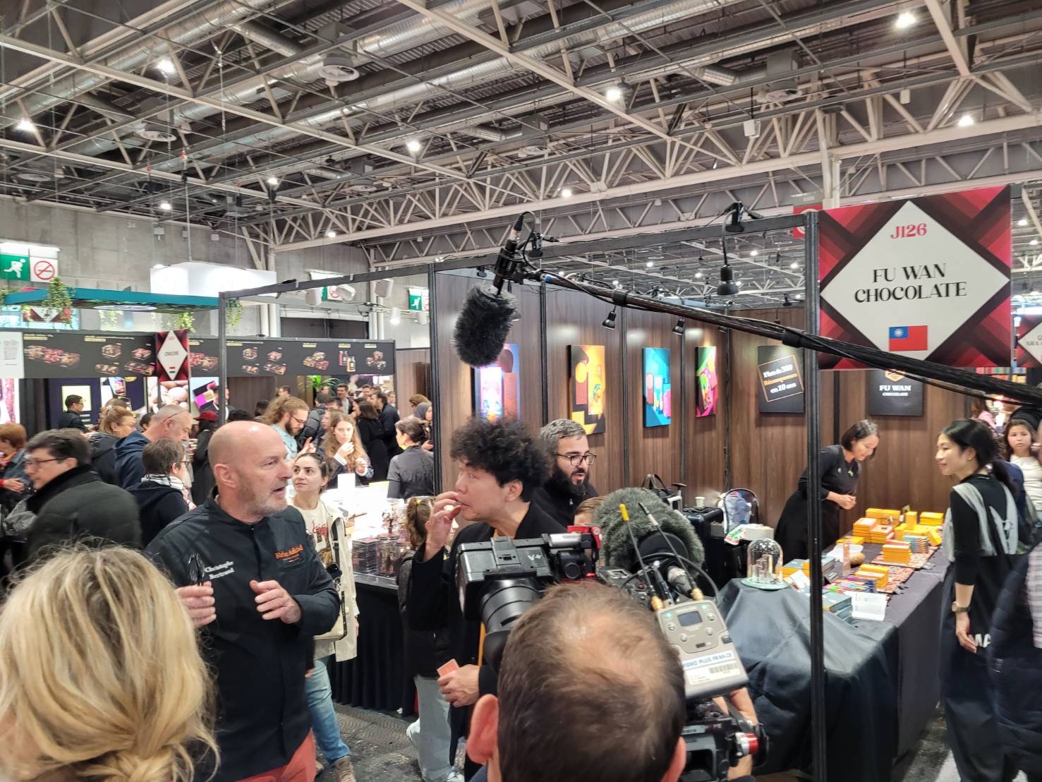 創辦人許華仁(中)於巴黎展位前受訪。圖/福灣巧克力提供